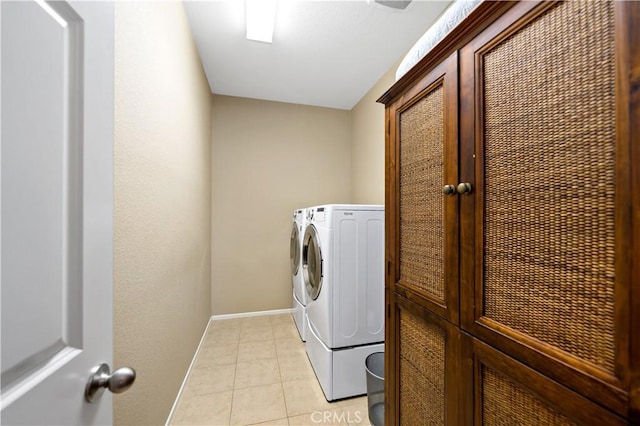 washroom featuring light tile patterned floors, separate washer and dryer, cabinet space, and baseboards