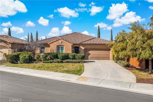 mediterranean / spanish-style house with stucco siding, concrete driveway, fence, a garage, and a tiled roof