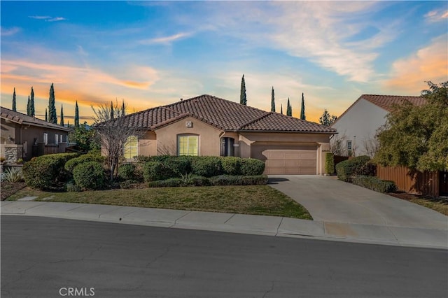 mediterranean / spanish-style house with an attached garage, a tile roof, concrete driveway, and stucco siding