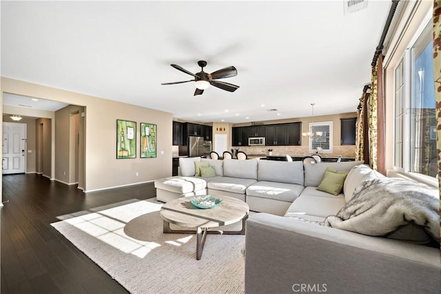 living room featuring dark wood-style floors, baseboards, visible vents, and a ceiling fan