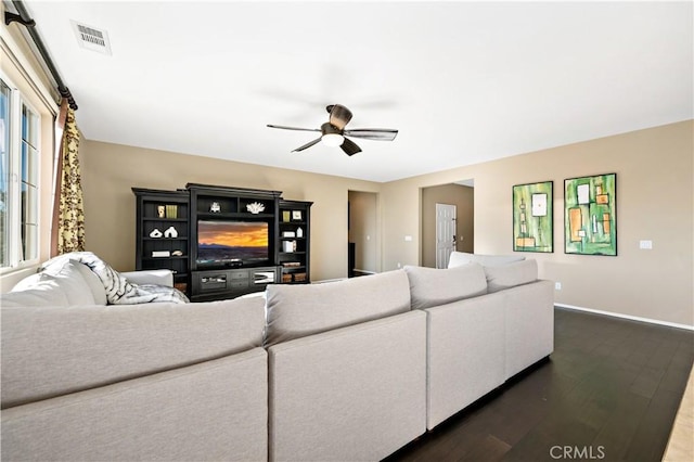 living area with visible vents, dark wood-style flooring, a ceiling fan, and baseboards