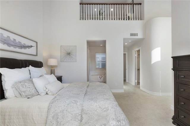 bedroom featuring light colored carpet, visible vents, a towering ceiling, ensuite bathroom, and baseboards