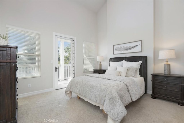 bedroom featuring light carpet, access to outside, a high ceiling, and baseboards