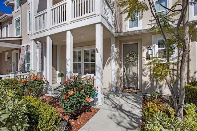 entrance to property featuring a porch and stucco siding