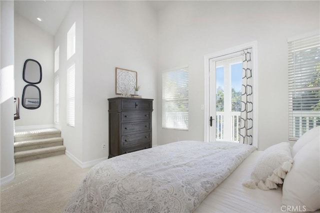 carpeted bedroom with high vaulted ceiling, multiple windows, and baseboards