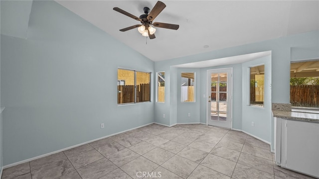 empty room featuring lofted ceiling, ceiling fan, light tile patterned flooring, and baseboards