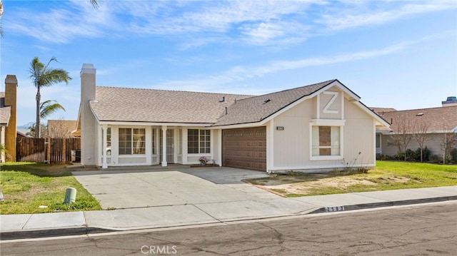 view of front of property featuring roof with shingles, concrete driveway, a front yard, fence, and a garage