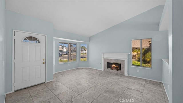 foyer featuring a high end fireplace, vaulted ceiling, baseboards, and light tile patterned floors