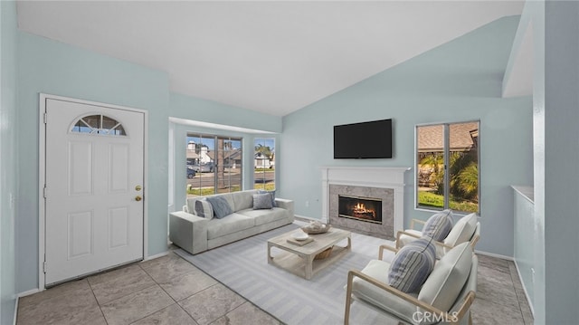 living area with a fireplace, vaulted ceiling, baseboards, and light tile patterned floors