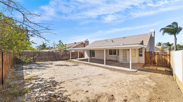 back of house featuring a patio area, a fenced backyard, a chimney, and stucco siding