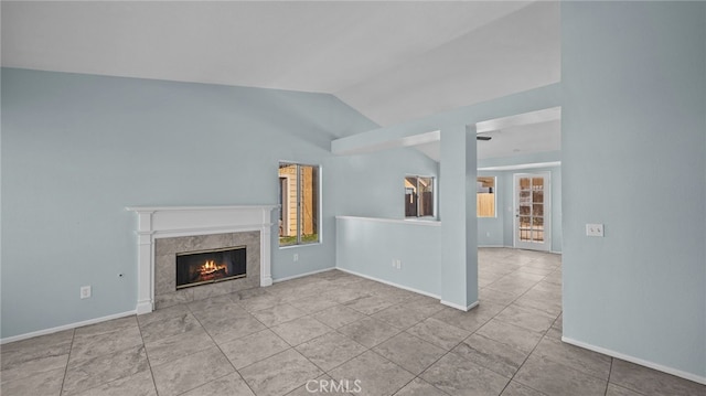 unfurnished living room featuring lofted ceiling, a premium fireplace, light tile patterned flooring, and baseboards