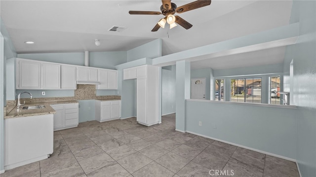 kitchen featuring visible vents, lofted ceiling, under cabinet range hood, white cabinetry, and a sink