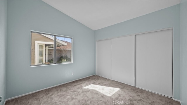 unfurnished bedroom featuring a closet, light colored carpet, and vaulted ceiling