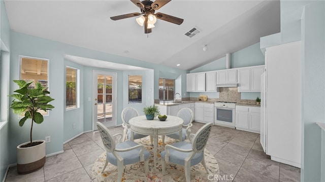 dining room with visible vents, a ceiling fan, light tile patterned flooring, vaulted ceiling, and baseboards