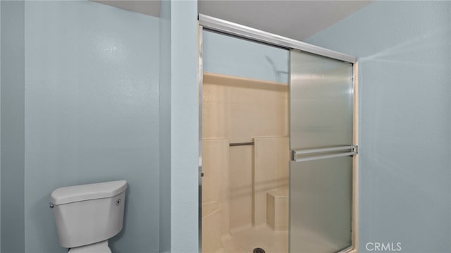 bathroom with a shower with door and toilet