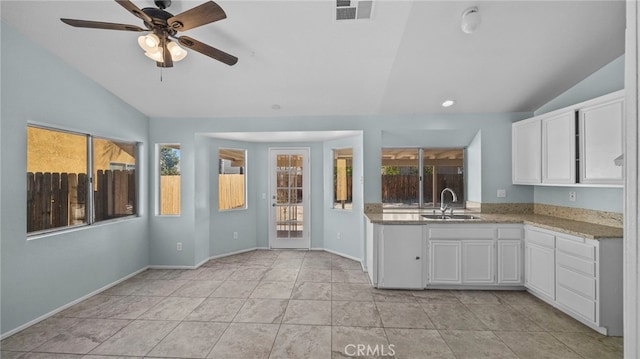 kitchen with lofted ceiling, white cabinets, a sink, and visible vents