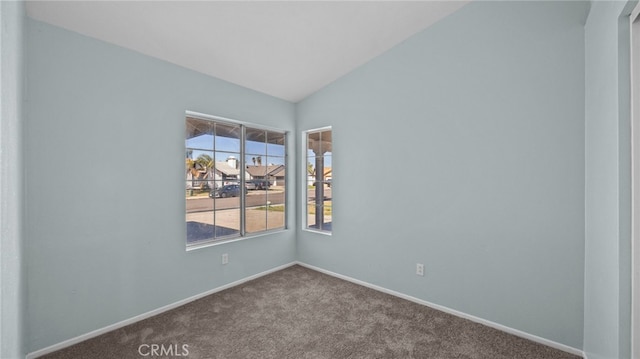 carpeted empty room featuring lofted ceiling and baseboards