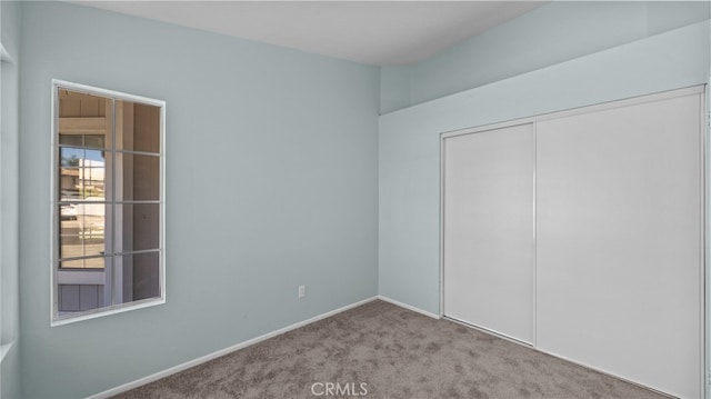 unfurnished bedroom featuring baseboards, a closet, and light colored carpet