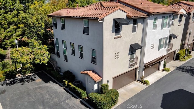 view of side of property with a tiled roof, driveway, and stucco siding