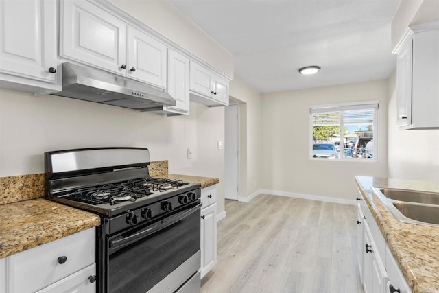 kitchen featuring baseboards, gas range, light wood-type flooring, under cabinet range hood, and white cabinetry