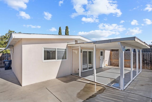 rear view of house featuring a patio, fence, and stucco siding