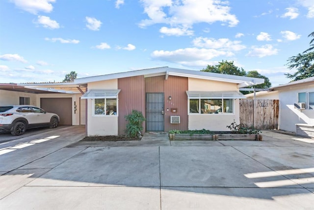 view of front of property featuring driveway, fence, and a carport