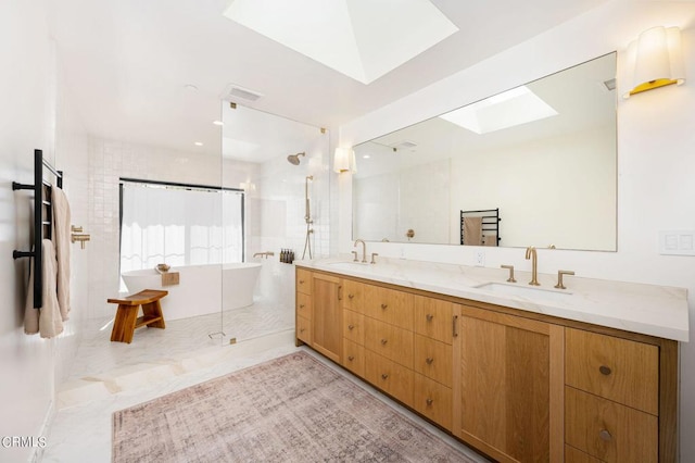 full bathroom with double vanity, a freestanding tub, a skylight, and a sink