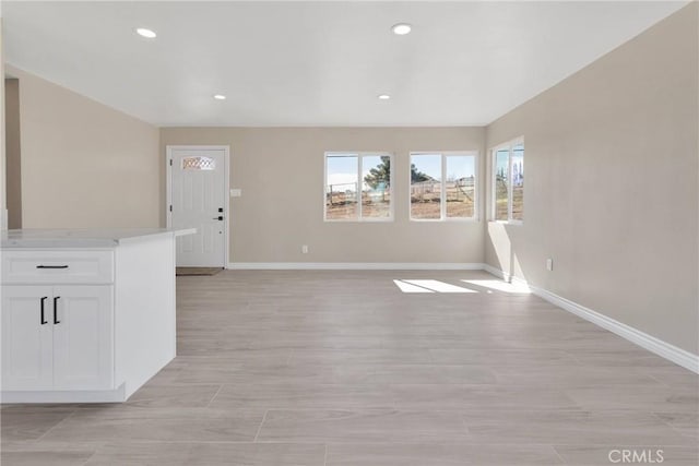 unfurnished living room featuring recessed lighting and baseboards