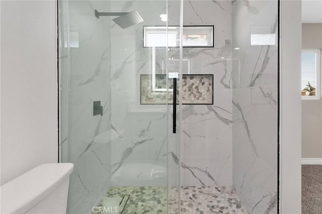 bathroom featuring toilet and a marble finish shower