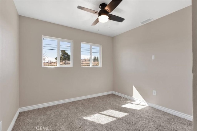 carpeted spare room featuring baseboards, visible vents, and ceiling fan