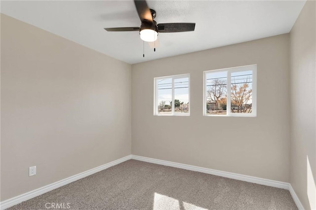 carpeted empty room with a ceiling fan and baseboards