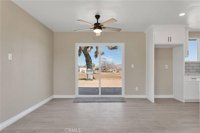 unfurnished dining area with a ceiling fan, recessed lighting, light wood-style floors, and baseboards