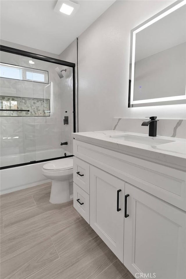 full bath featuring enclosed tub / shower combo, vanity, and toilet