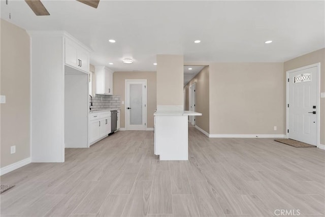 kitchen featuring white cabinets, stainless steel dishwasher, light countertops, and decorative backsplash