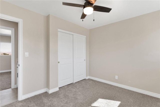 unfurnished bedroom with baseboards, ceiling fan, a closet, and light colored carpet