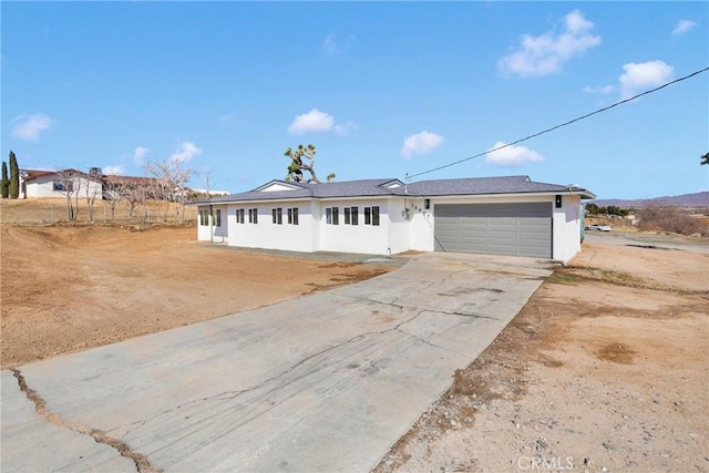 ranch-style house with concrete driveway, an attached garage, and stucco siding