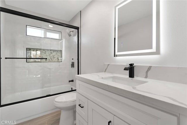 full bathroom with enclosed tub / shower combo, vanity, toilet, and wood finished floors