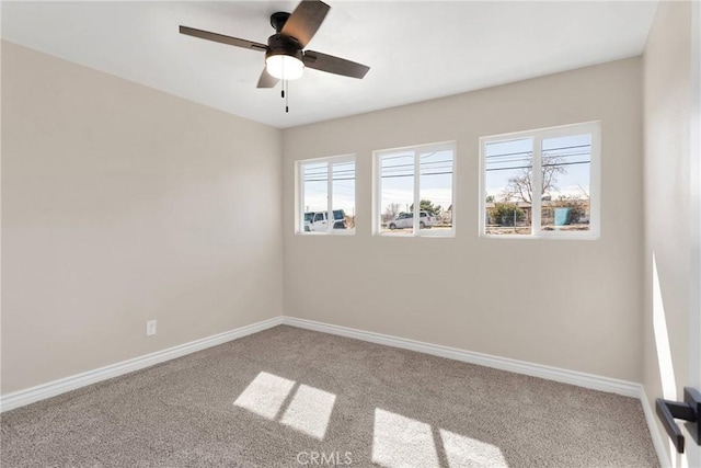 carpeted empty room featuring ceiling fan, baseboards, and a wealth of natural light