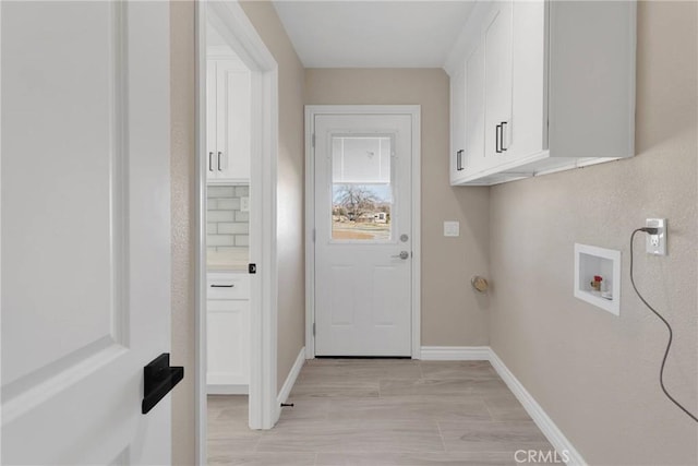 clothes washing area with light wood-style flooring, washer hookup, cabinet space, and baseboards