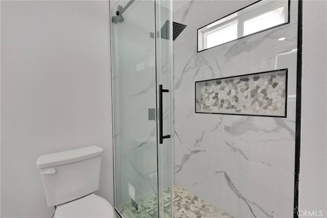 bathroom featuring toilet and a marble finish shower