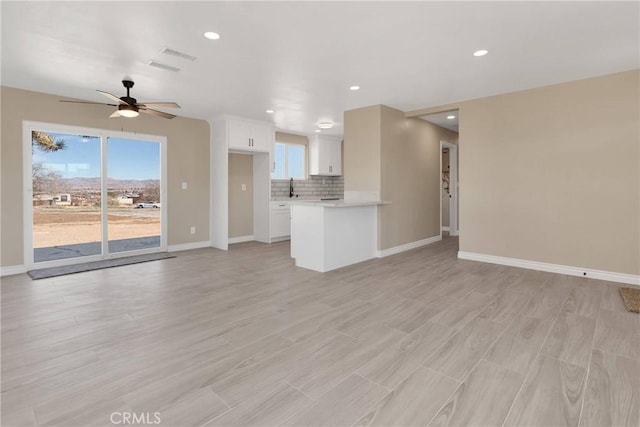 unfurnished living room with light wood-style floors, a wealth of natural light, and baseboards