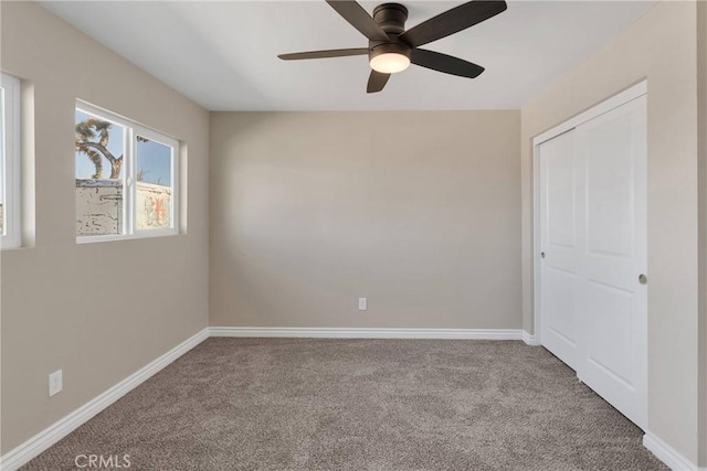 carpeted empty room with ceiling fan and baseboards