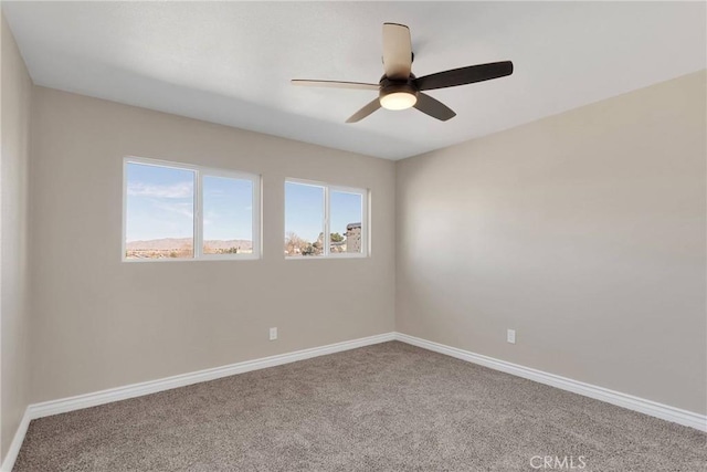 carpeted empty room featuring baseboards and a ceiling fan