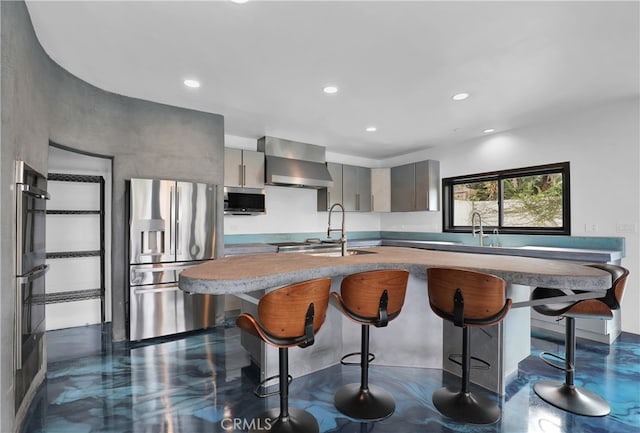 205 Esplanade, San Clemente, CA 92672 - kitchen featuring wall chimney range hood, stainless steel appliances, gray cabinetry, and a kitchen breakfast bar