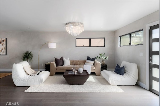 living area featuring a notable chandelier, baseboards, and wood finished floors