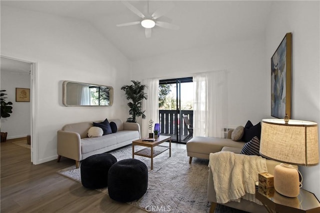 living area with a ceiling fan, vaulted ceiling, baseboards, and wood finished floors