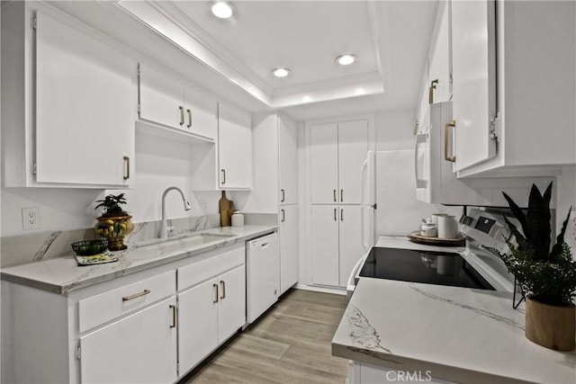 kitchen with light wood-style flooring, white appliances, a sink, white cabinets, and a raised ceiling