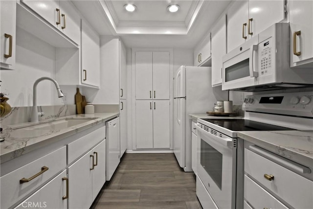 kitchen with a tray ceiling, ornamental molding, white cabinetry, a sink, and white appliances