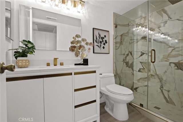 full bathroom featuring toilet, a marble finish shower, visible vents, and vanity