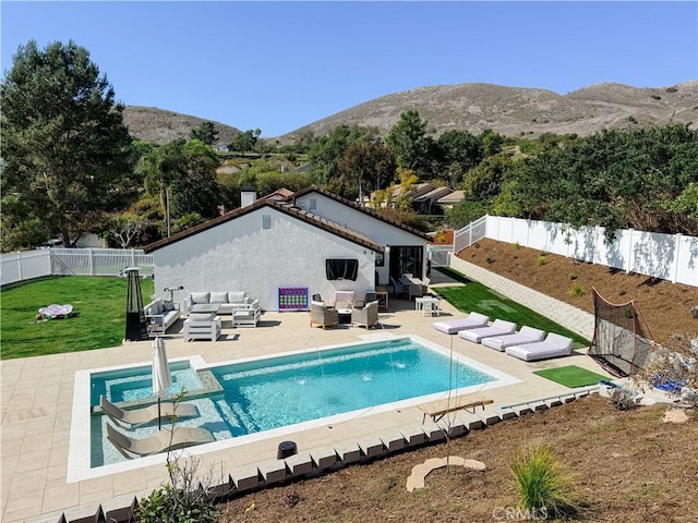 rear view of house featuring a patio, a fenced backyard, a mountain view, an outdoor hangout area, and a lawn